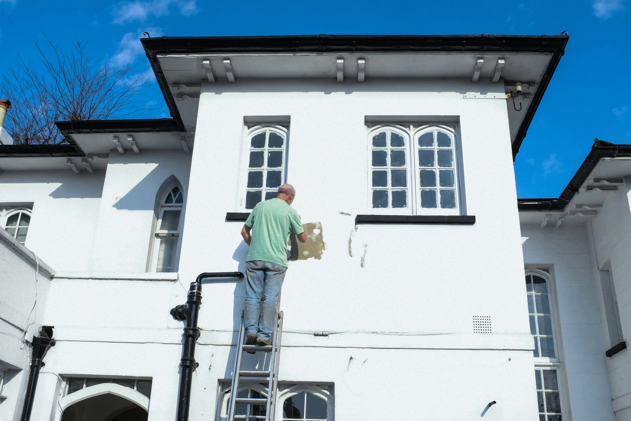 Painter standing on exterior building wall in daytime