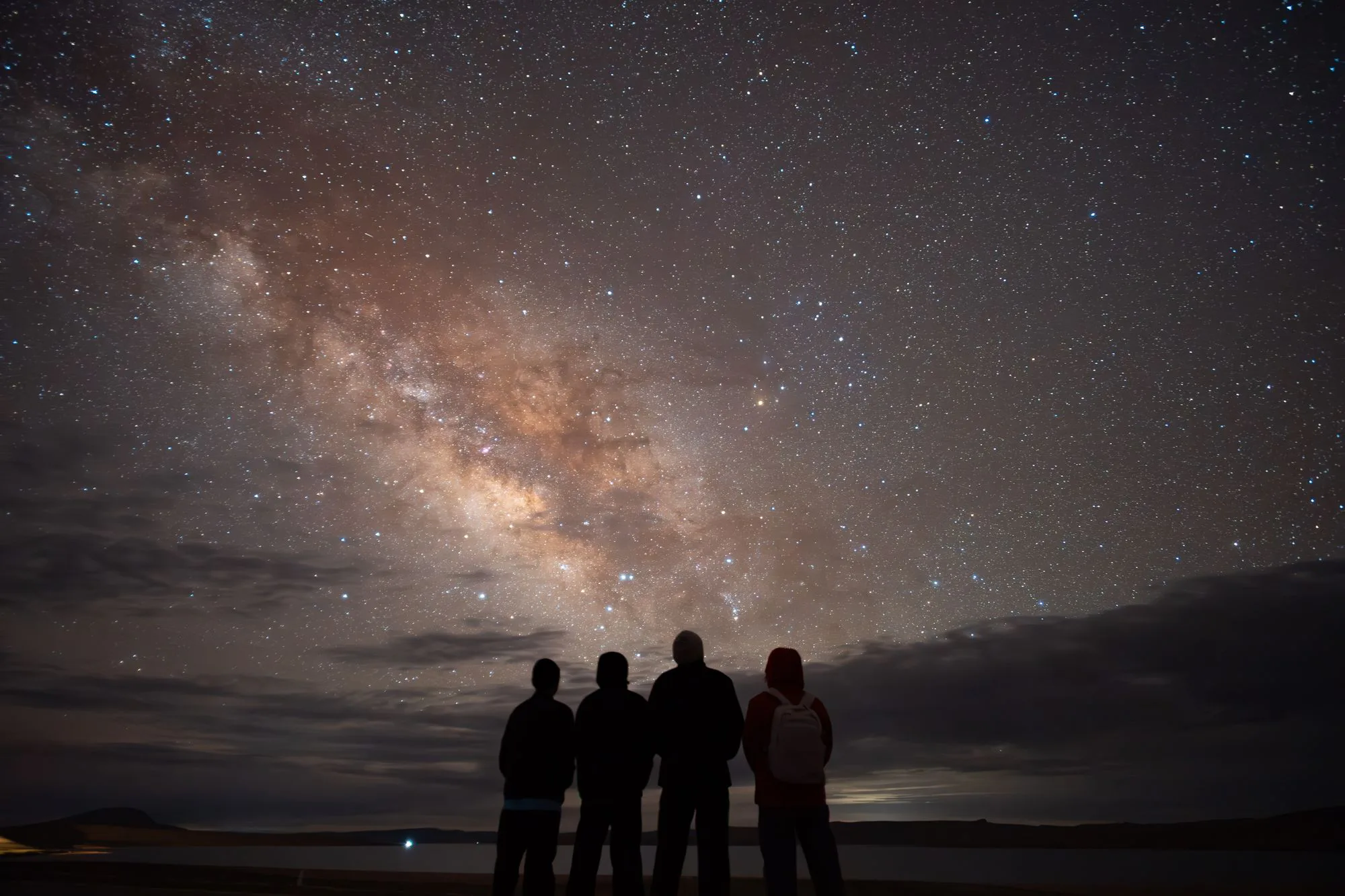 Teens silhouetted together under a starry night sky