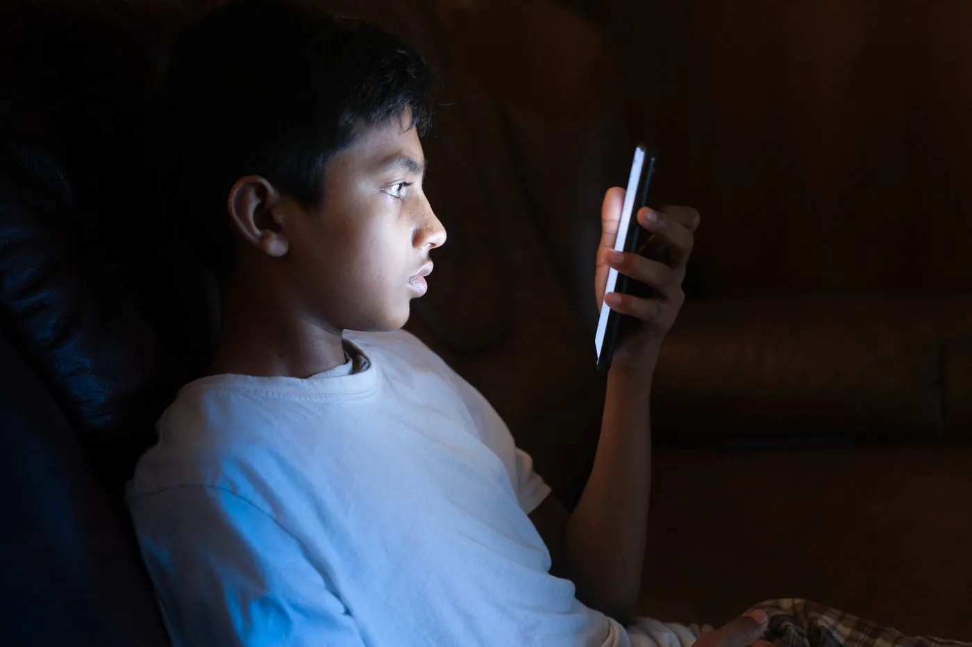 Teen alone at night lit only by phone screen
