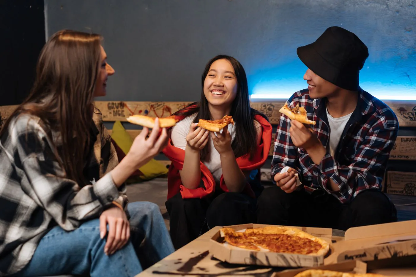 Teens laughing together over pizza at a meal