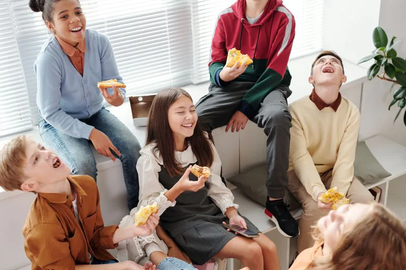 Teenagers laughing and eating pizza together