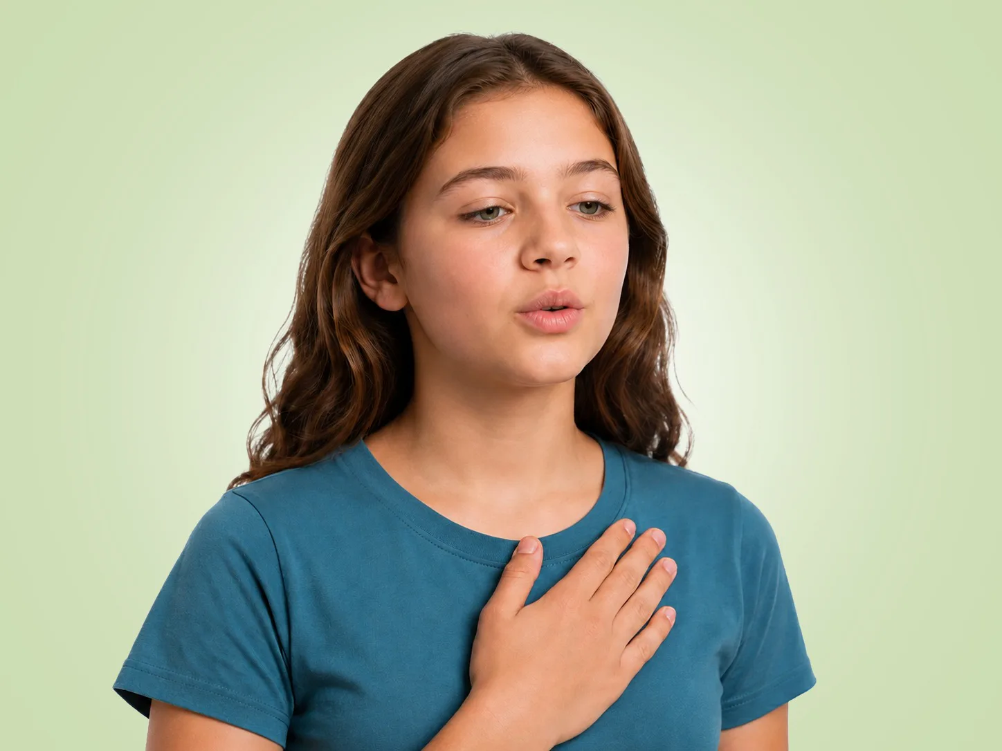 A young girl with wavy brown hair wearing a teal shirt, placing her hand on her chest and breathing calmly.