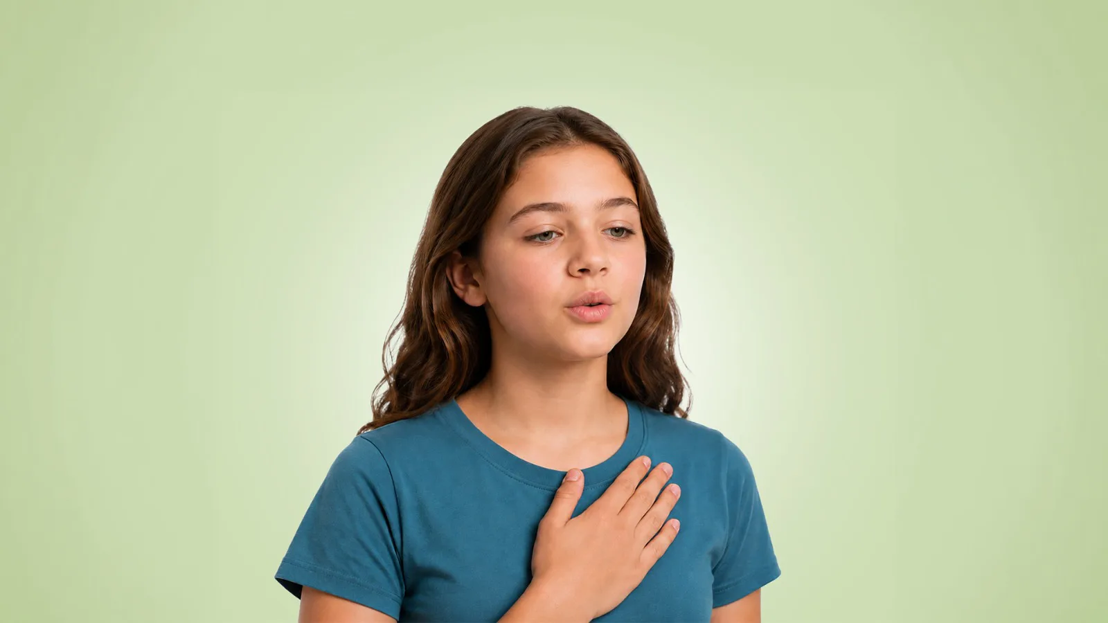 A young girl with wavy brown hair wearing a teal shirt, placing her hand on her chest and breathing calmly.