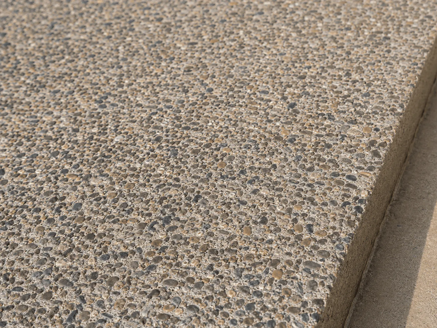 Rounded natural stone exposed evenly in a concrete surface