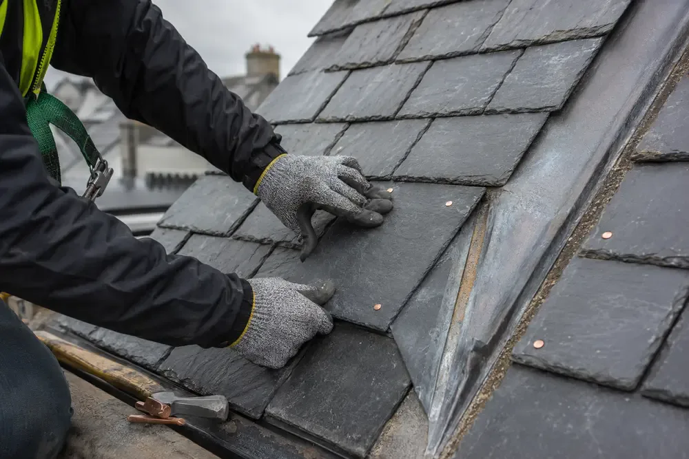 Professional slate repair beside a lead roof valley