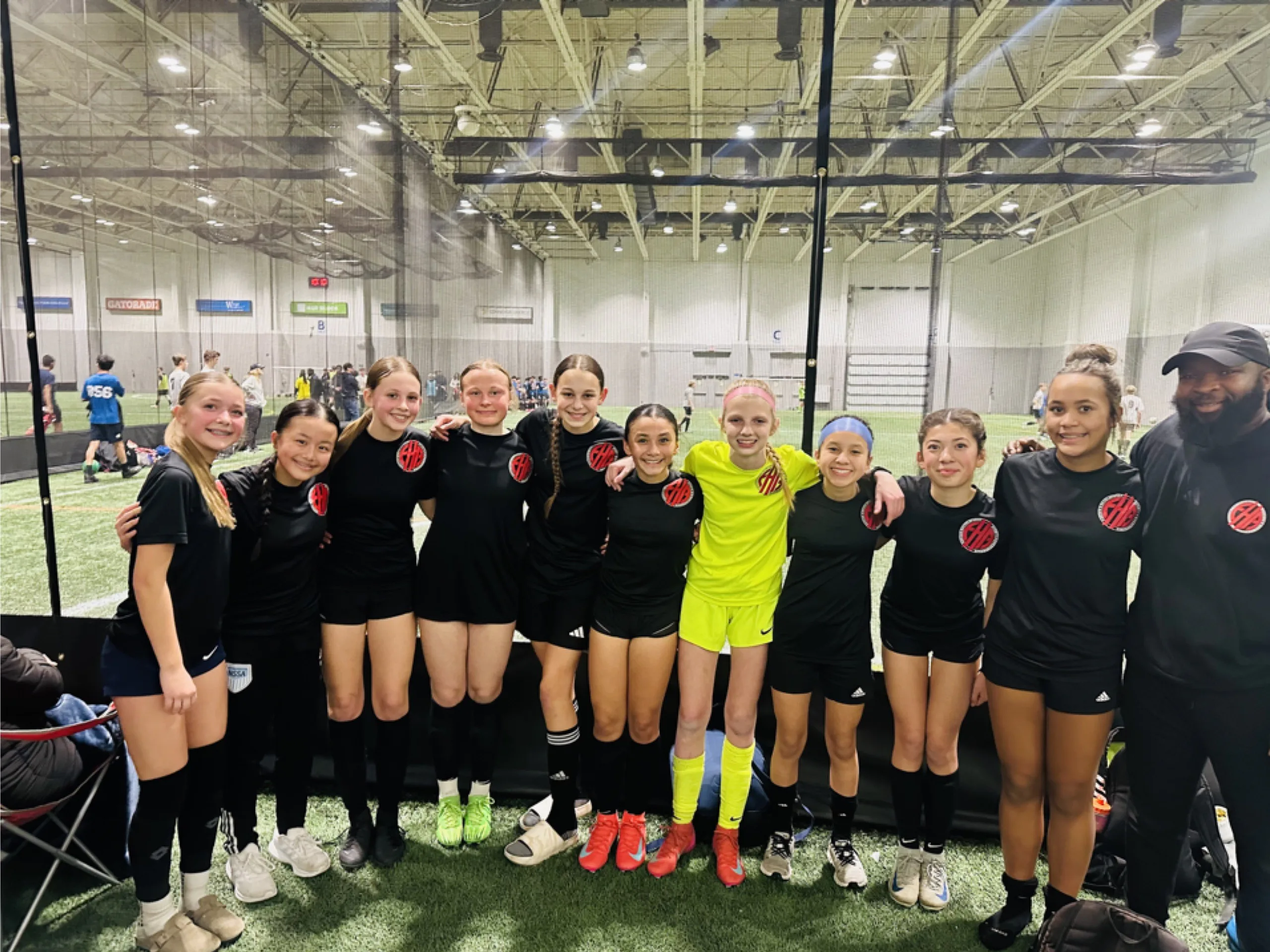 Coach Mulenga and EdHope youth athletes posing at an indoor soccer facility