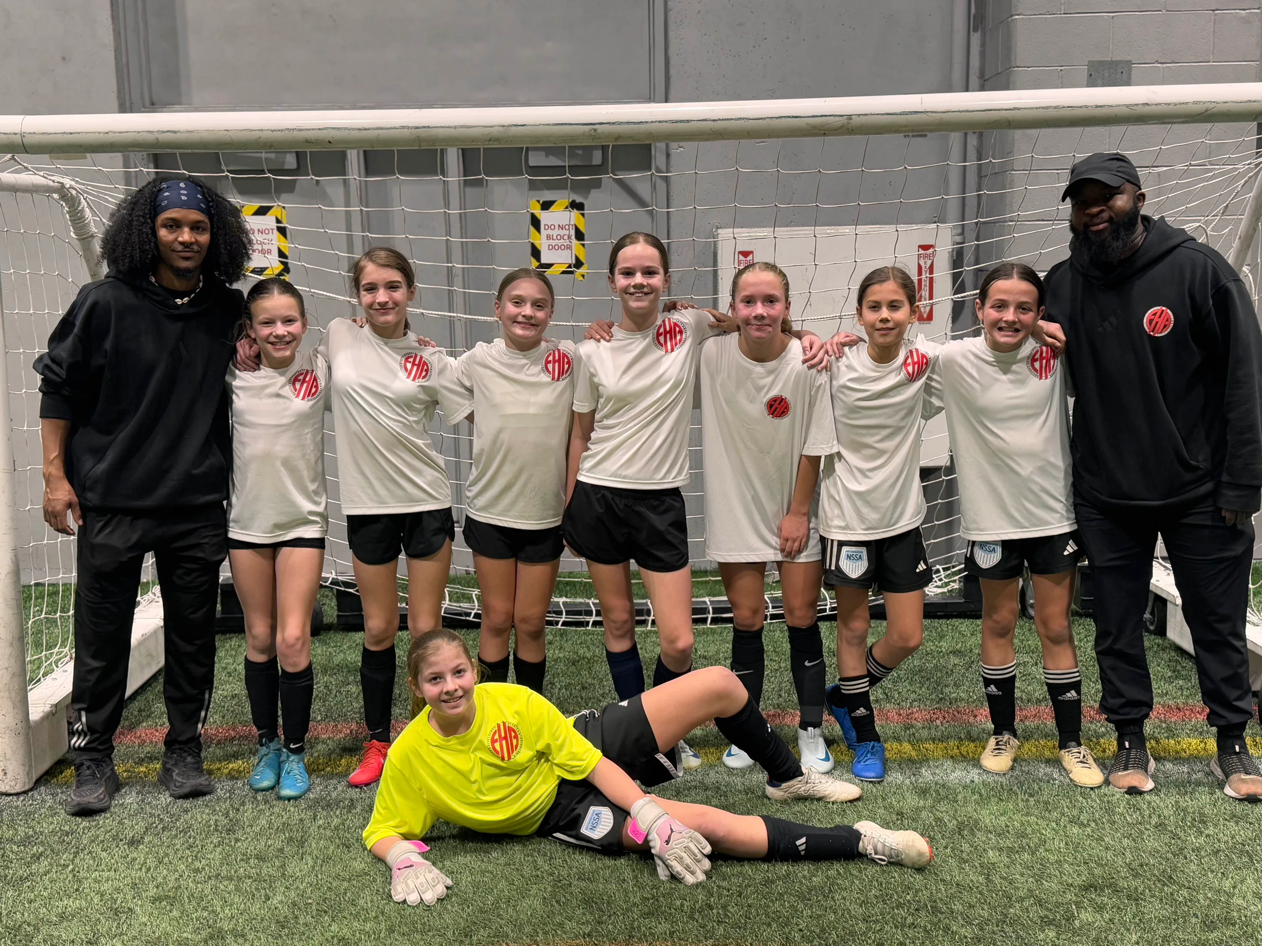 EdHope coaching staff and youth athletes posing in front of an indoor soccer goal
